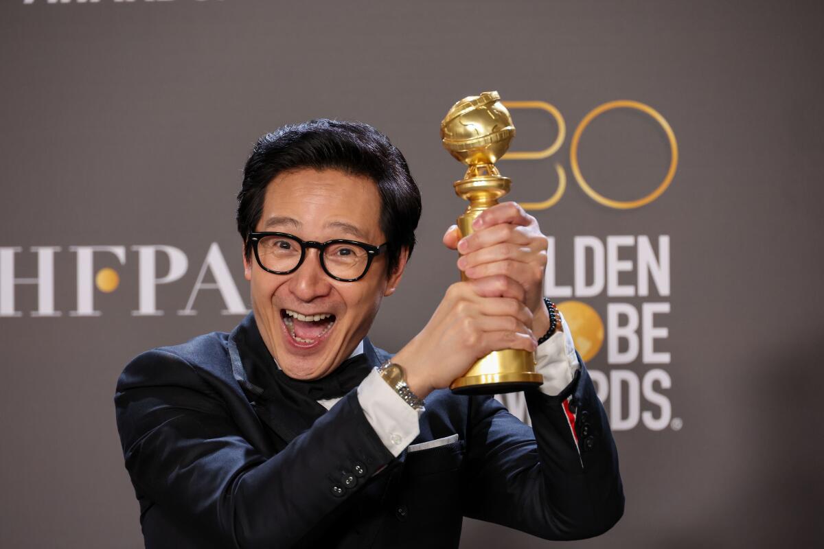 Actor Ke Huy Quan holds his Golden Globe up with a big smile on his face.