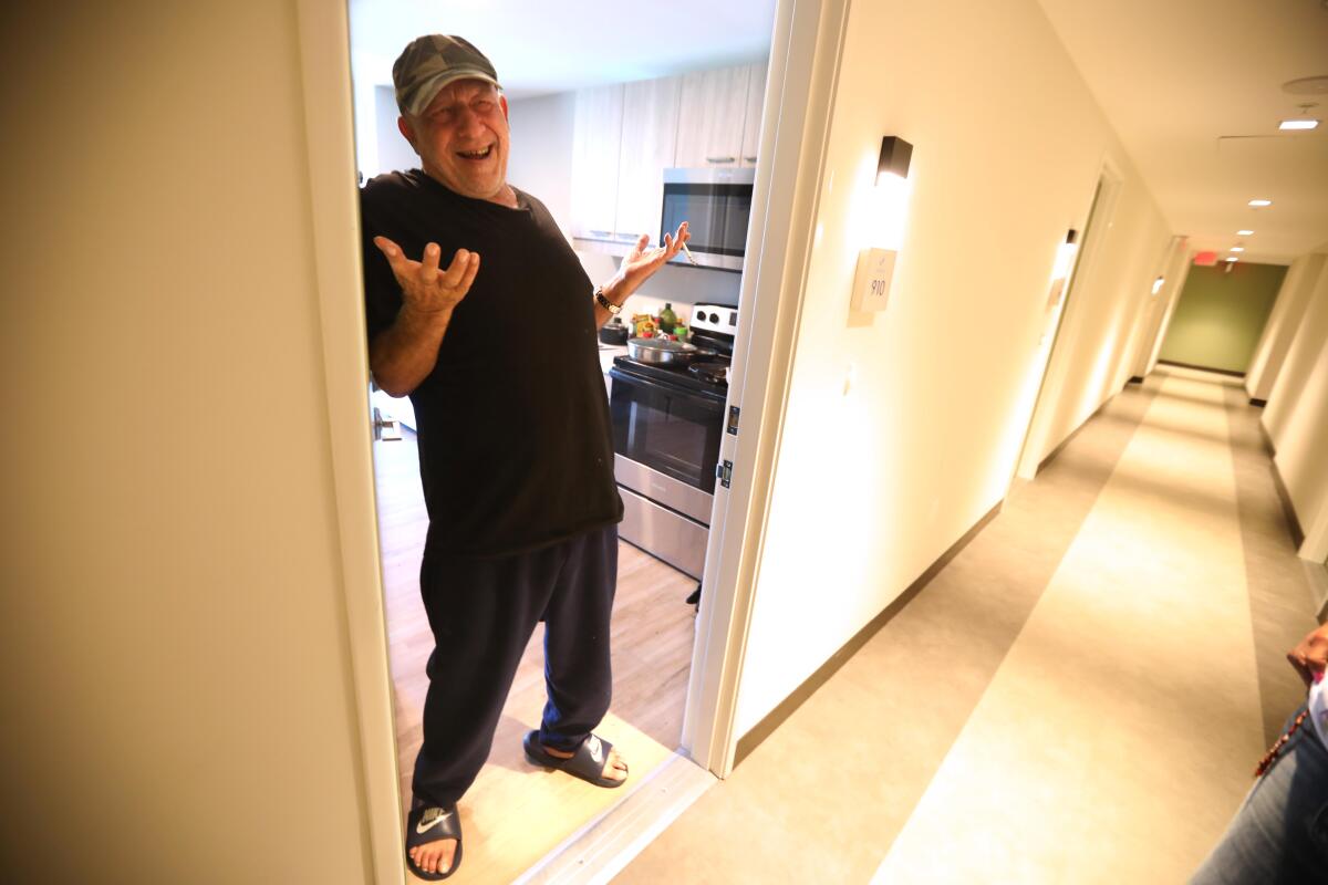 A man smiles in an apartment doorway.