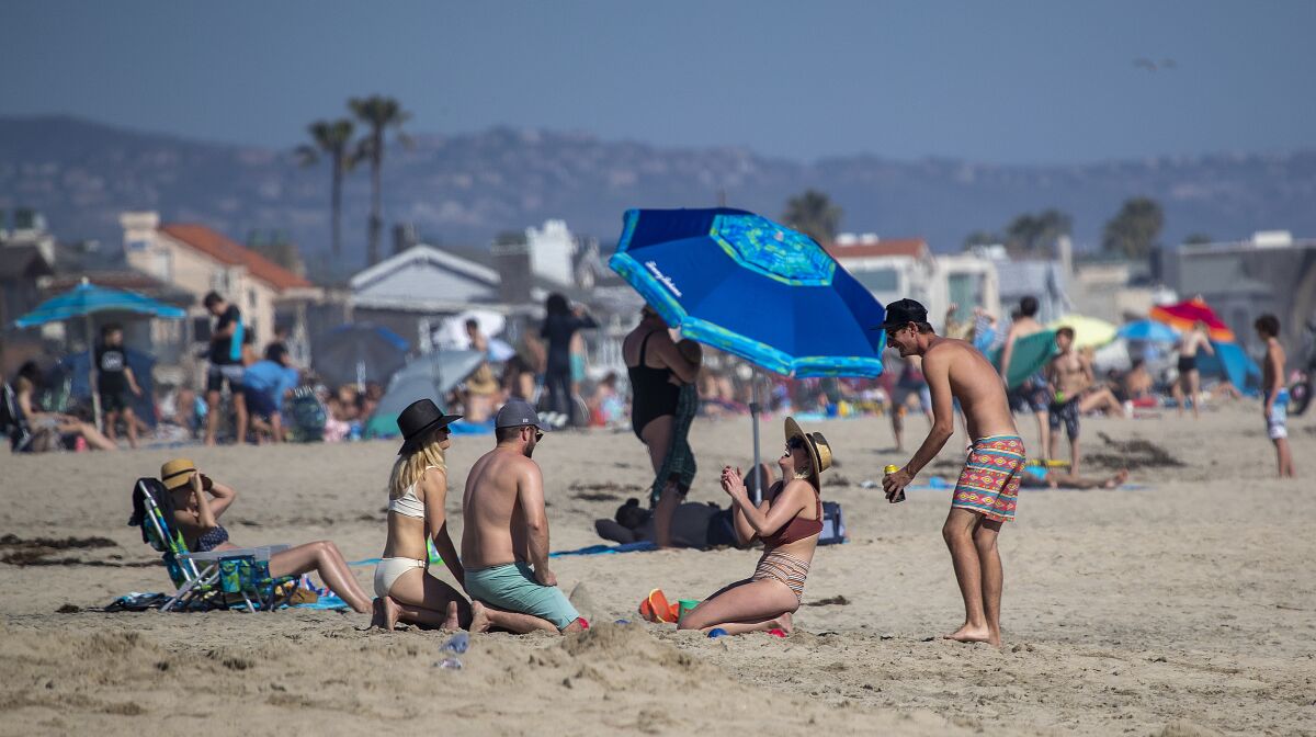 Beachgoers enjoy a warm, sunny Saturday in Newport Beach amid state-mandated stay-at-home orders.
