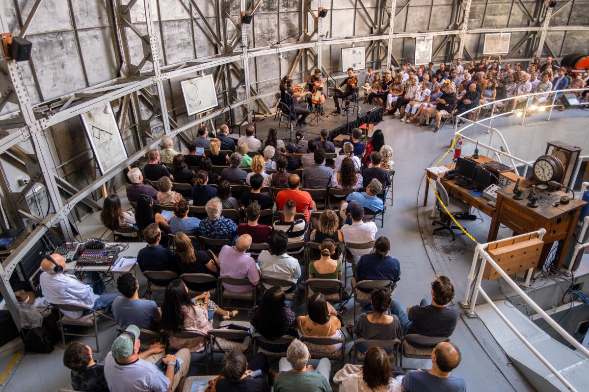 A crowd enjoys a performance by a string quartet inside the dome of an observatory.
