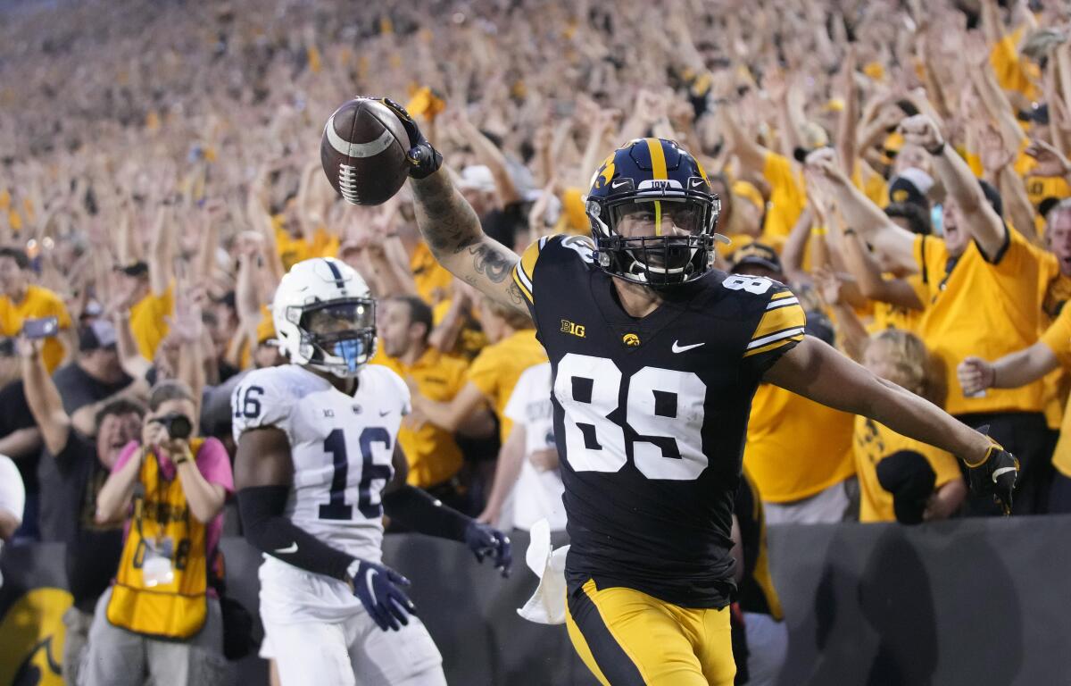 Iowa wide receiver Nico Ragaini (89) reacts after scoring a touchdown in front of Penn State safety Ji'Ayir Brown (16) during the second half of an NCAA college football game, Saturday, Oct. 9, 2021, in Iowa City, Iowa. Iowa won 23-20. (AP Photo/Matthew Putney)