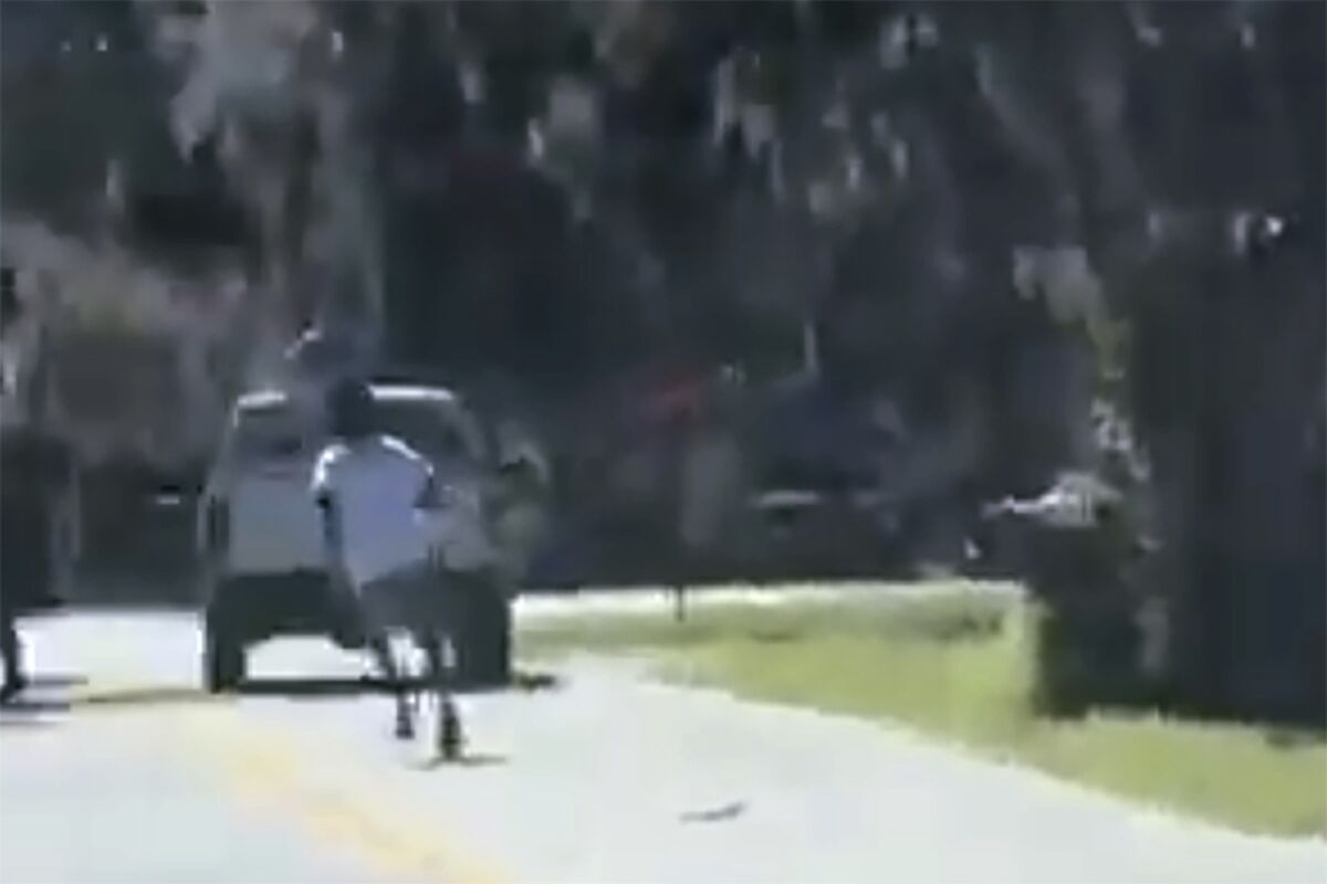 This image from video posted on Twitter Tuesday, May 5, 2020, purports to show Ahmaud Arbery running on a street in a neighborhood outside Brunswick, Ga., on Feb. 23, 2020, as a pickup truck is stopped in front of him. Two men in the truck, Travis McMichael and his father, Gregory McMichael, confronted Arbery and less than a minute later he was fatally shot. The AP has not been able to verify the source of the video. Father and son Greg and Travis McMichael and their neighbor, William “Roddie” Bryan, face an automatic life sentence if they're convicted of murder in Glynn County Superior Court. The three white men in pickup trucks pursed Arbery, a 25-year-old Black man, after spotting him running in their neighborhood last year (Twitter via AP)