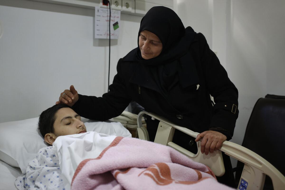 Pro-government Syrian student Hani Ali Hassan, 19, is comforted by his mother, Khadijah Sheikh Haidar, at a hospital south of Beirut on Dec. 30 after being evacuated from the besieged Shiite Muslim village of Fuaa, Syria.