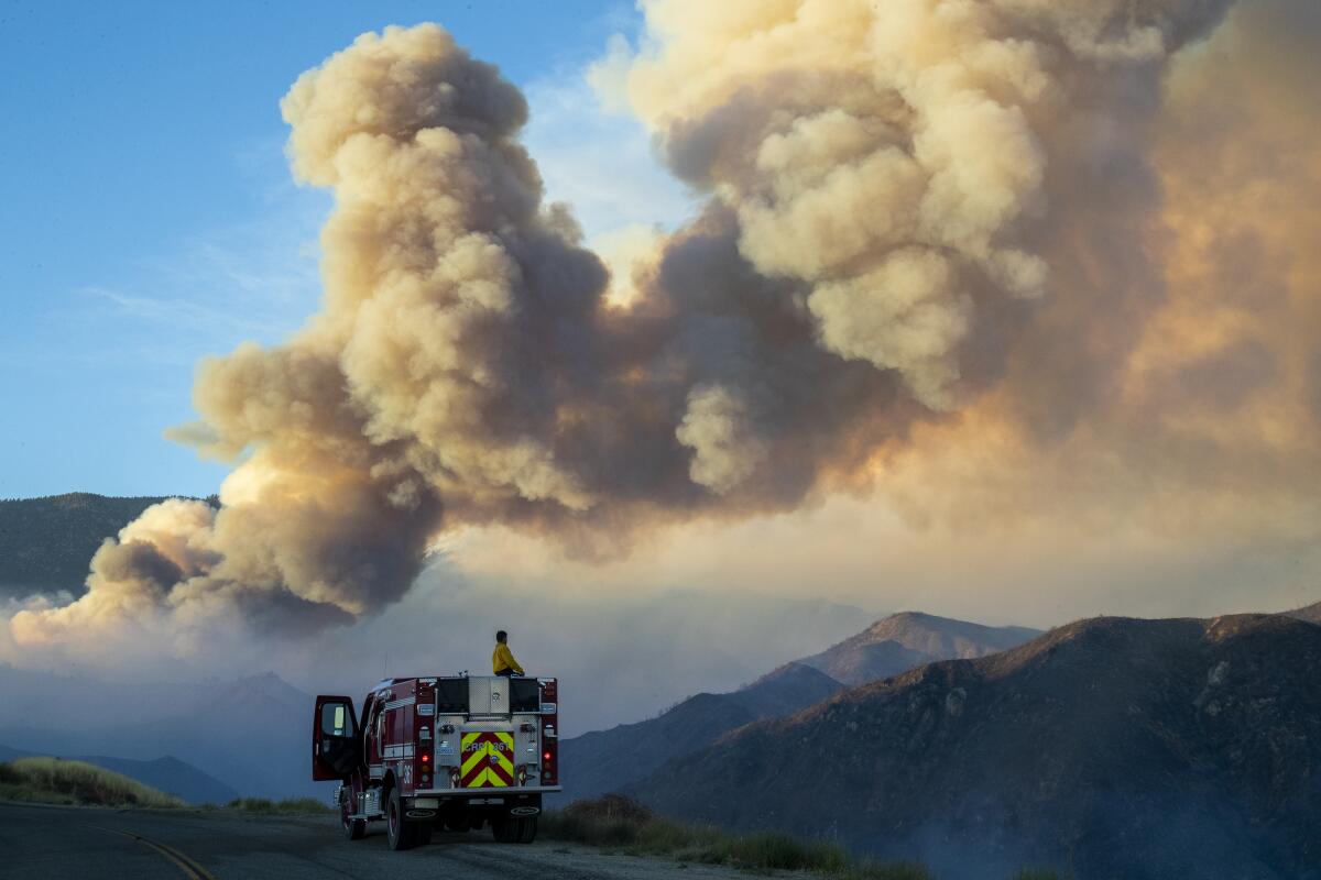 A firefighter looks at a huge plume of smoke from the Apple fire