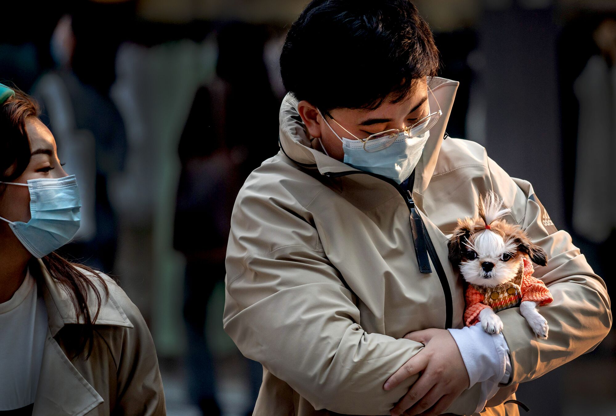 CHINA: A man (R) wearing a facemask amid the concerns over the COVID-19 coronavirus holds a dog as he walks at a shopping mall in Beijing on April 9, 2020.