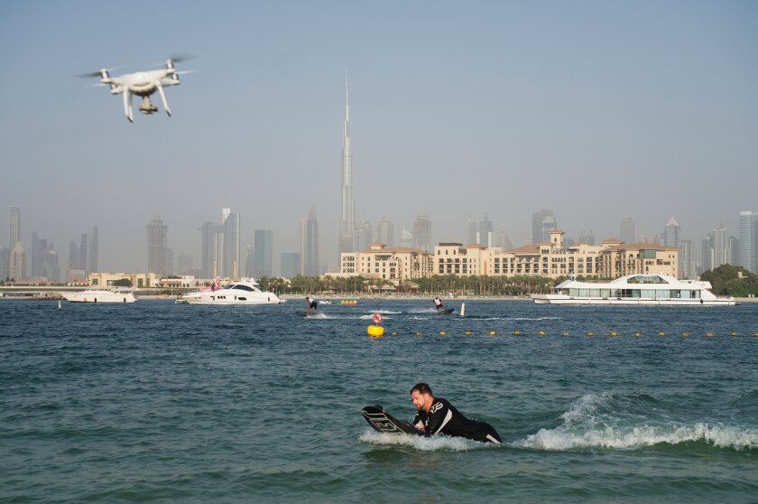 FILE - A drone follows a man riding a motorized surfboard in Dubai, United Arab Emirates, June 25, 2020. The UAE has banned the flying of drones in the country for recreation after Yemen’s Houthi rebels claimed a fatal drone attack on an oil facility and major airport in the country. As of Saturday, Jan. 22, 2022, drone hobbyists and other operators of light electric sports aircraft face “legal liabilities” if caught flying the objects, the Interior Ministry said, adding it may grant exemptions to businesses seeking to film. (AP Photo/Jon Gambrell, File)