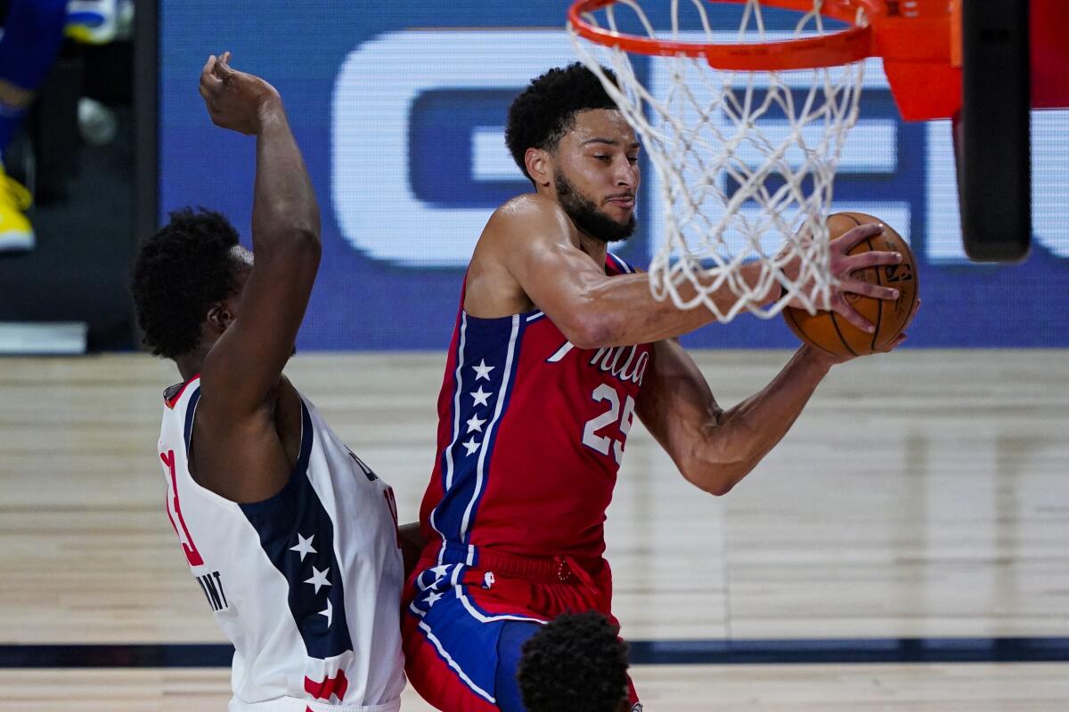 76ers guard Ben Simmons grabs a rebound in front of Wizards center Thomas Bryant during their game Wednesday.