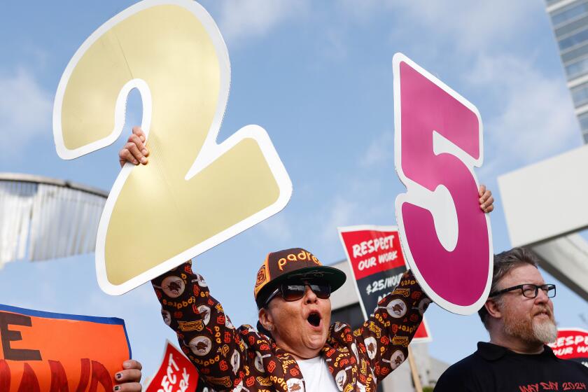 San Diego, CA - May 01: Monica Marin, of Chula Vista, holds up cardboard numbers during a protest for hospitality workers to make a minimum wage of $25/Hour at San Diego Bayfront Park on Wednesday, May 1, 2024 in San Diego, CA. (Meg McLaughlin / The San Diego Union-Tribune)
