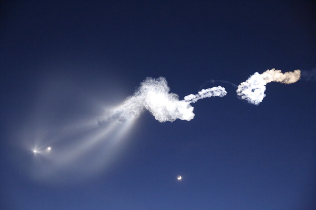 First-stage separation is seen at left, with the moon below, as SpaceX launches its Falcon 9 rocket, its final mission of the year, from Vandenburg Air Force Base in California.