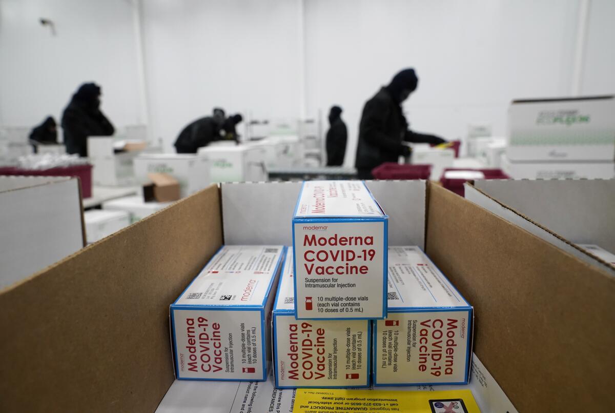 Boxes labeled "Moderna COVID-19 vaccine" are stacked at a distribution center.