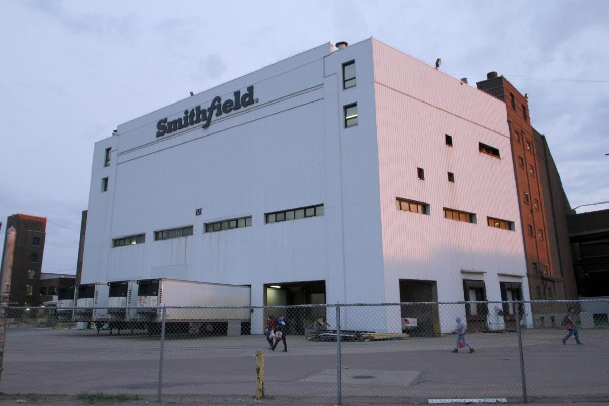 FILE - Employees of two departments at the Smithfield pork processing plant in Sioux Falls, S.D., report to work, May 4, 2020. Smithfield Foods will pay restaurants and caterers $42 million to settle a lawsuit that accused the giant meat producer of conspiring to inflate pork prices. Smithfield didn't admit any wrongdoing but the deal will likely only add to concerns about how the lack of competition in the industry affects meat prices. Lawyers began notifying companies affected by the settlement Tuesday, July 5, 2022. (AP Photo/Stephen Groves, File)