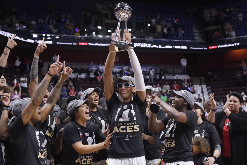 Las Vegas Aces' A'ja Wilson holds up the championship trophy as she celebrates with her team.