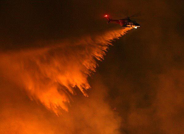 An L.A. County fire helicopter drops water on a canyon park area near Park Place and Crenshaw Boulevard in Rancho Palos Verdes.