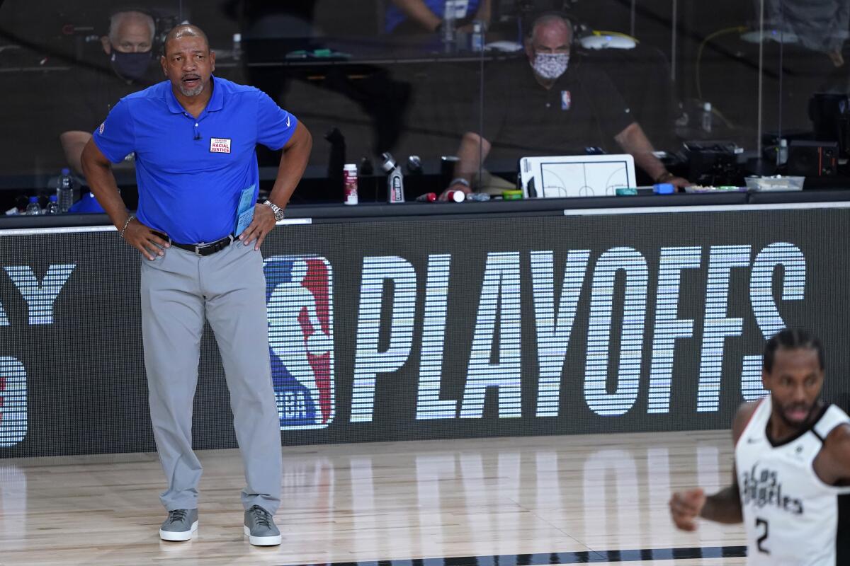 Los Angeles Clippers head coach Doc Rivers stands on the sideline with hands on hips.