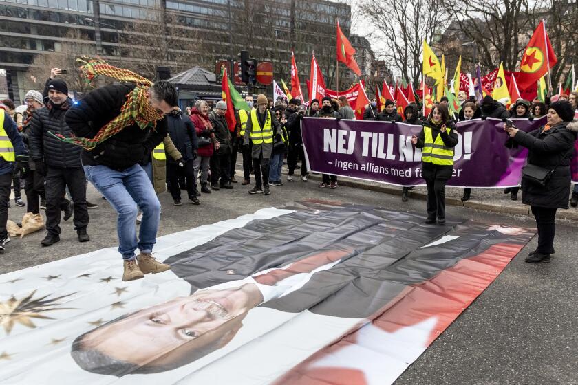 A protestor prepares to jump on a banner with the image of Turkish President Recep Tayyip Erdogan during a demonstration organised by The Kurdish Democratic Society Center in Sweden, as Sweden seeks Turkey's approval to join NATO, in Stockholm, Saturday, Jan. 21, 2023. Demonstrations took place in Sweden that could complicate its efforts to persuade Turkey to approve its NATO accession. A far-right activist from Denmark has received permission from police to stage a protest on Saturday outside the Turkish Embassy, where he intends to burn the Quran, Islam’s holy book. (Christine Olsson/TT News Agency via AP)