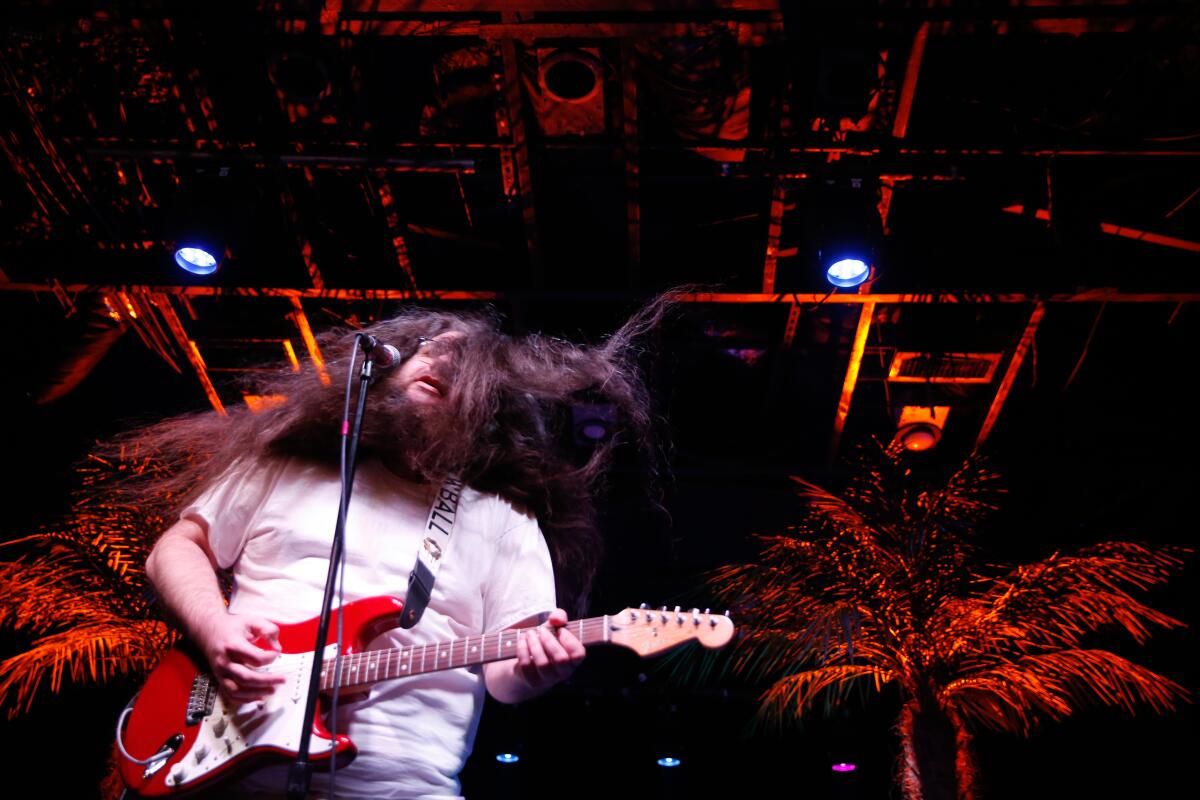 Man with long hair playing guitar onstage