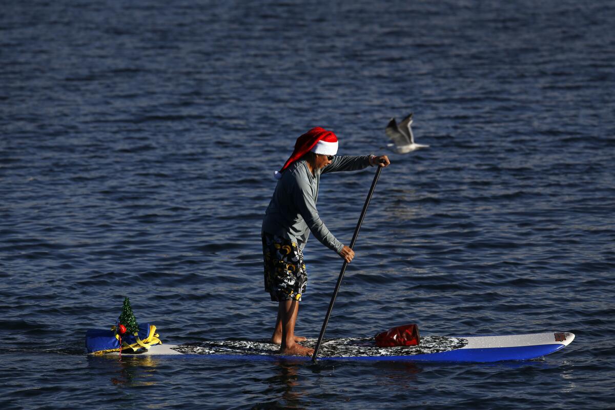 Cool, dry weather -- with a slight chance of rain Tuesday or Wednesday -- is expected through New Year's Day. Above, Dave Martinez, 56, of Whittier, paddles in Alamitos Bay on Dec. 25.