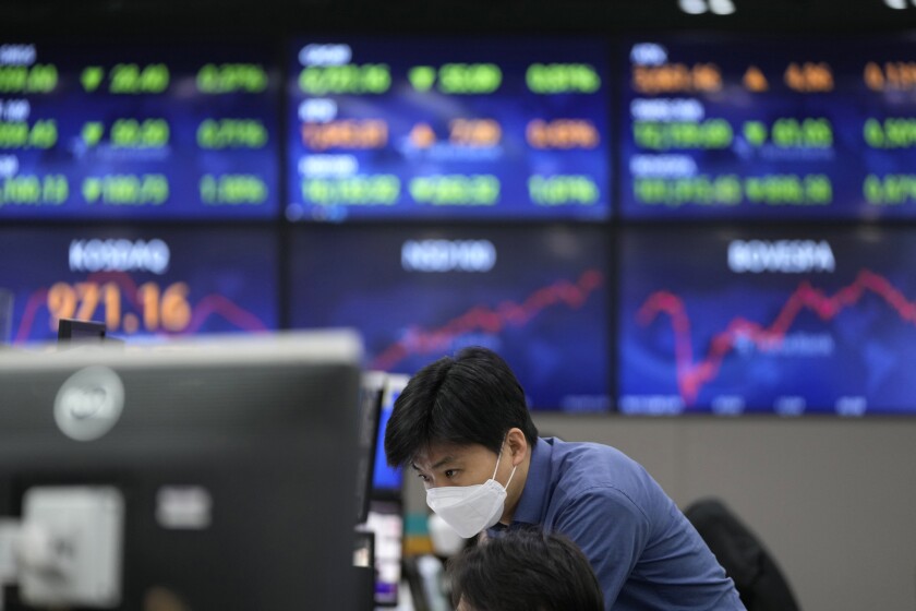 A currency trader watches computer monitors near the screens at a foreign exchange dealing room in Seoul, South Korea, Wednesday, Dec. 1, 2021. Asian shares were mixed Wednesday amid nervous trading due to worries over the newest coronavirus variant. (AP Photo/Lee Jin-man)