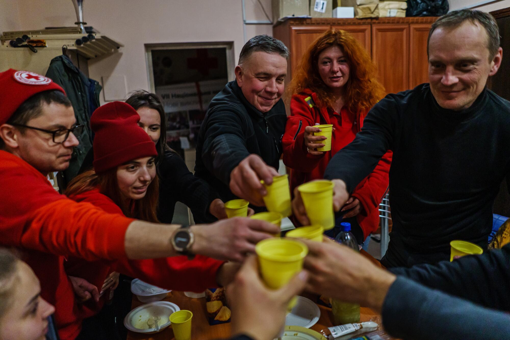 A group of workers holding yellow cups gather into the center to cheers one another.