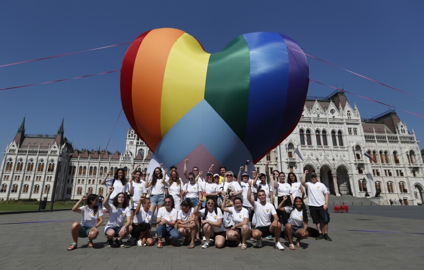 Activists pose for a photo after erecting a large rainbow-colored heart in front of the country's parliament building in Budapest, Hungary, on Thursday, July 8, 2021. The activists are protesting against the recently passed law they say discriminates and marginalizes LGBT people. (AP Photo/Laszlo Balogh)