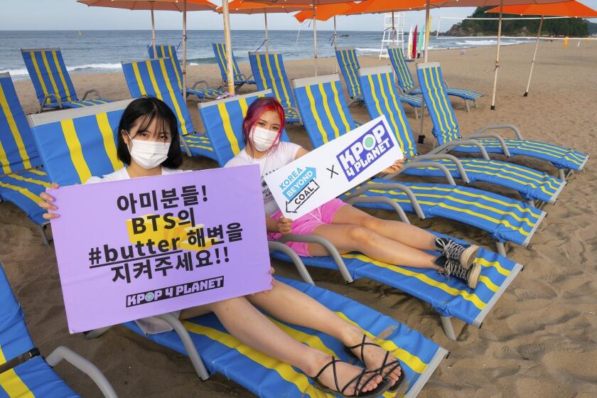 In this image provided by Kpop4Planet, demonstrators pose at Maengbang Beach in Samcheok, South Korea, as part of the #SaveButterBeach campaign in September 2021. The group paired with climate groups in South Korea to raise awareness about plans for a coal-burning power plant. The plant site is near the beach of the photo shoot location for album artwork for one of K-pop band BTS’s hit songs. (Soojung Do/Kpop4Planet via AP)