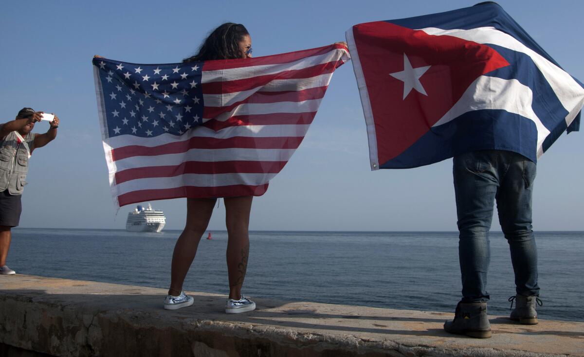 Yaney Cajigal, left, and Dalwin Valdes hold up U.S. and Cuban flags Monday as they watch the arrival of Fathom's Adonia cruise ship in Havana,