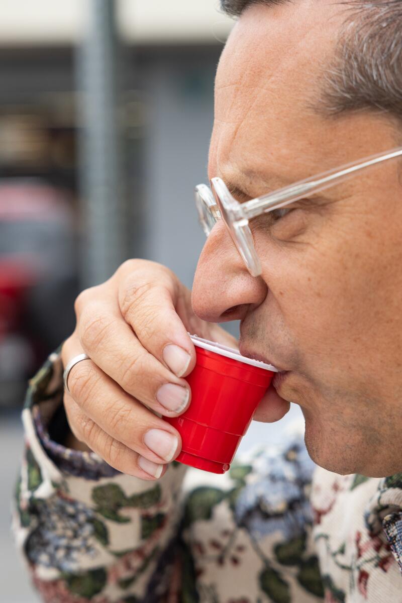 A closeup of a man drinking out of a small red Solo cup.