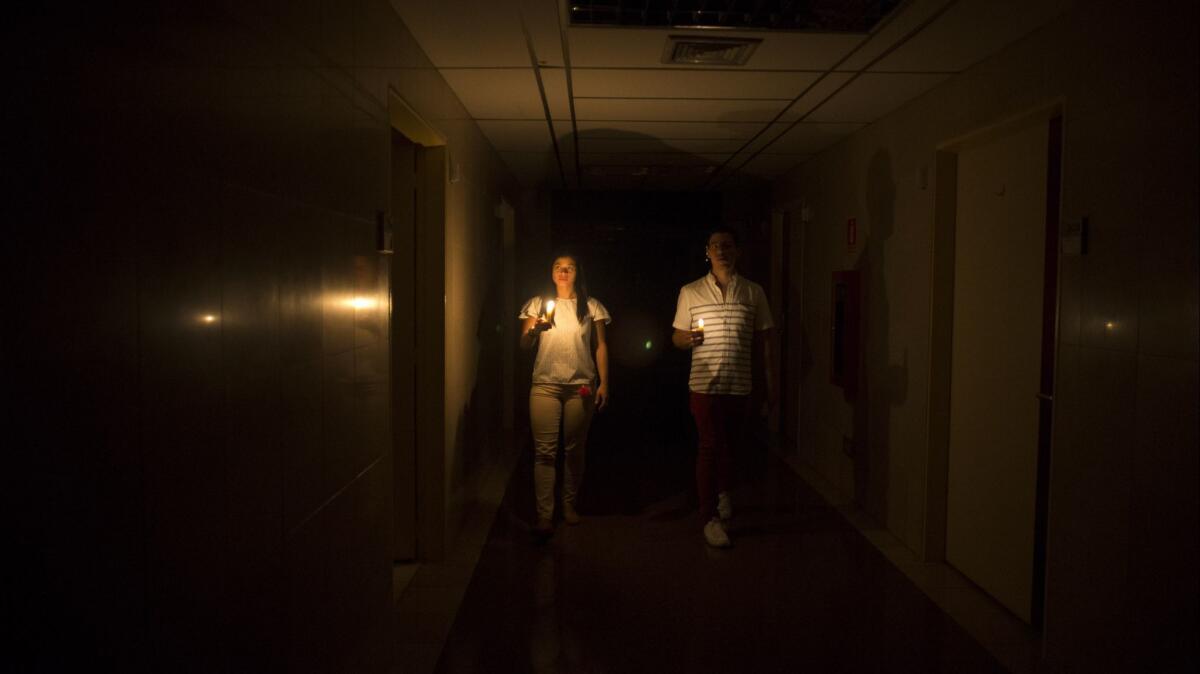 Relatives of a patient hold candles in a darkened clinic March 7 during a power outage in Caracas, Venezuela. The nationwide blackout lasted into the next afternoon.