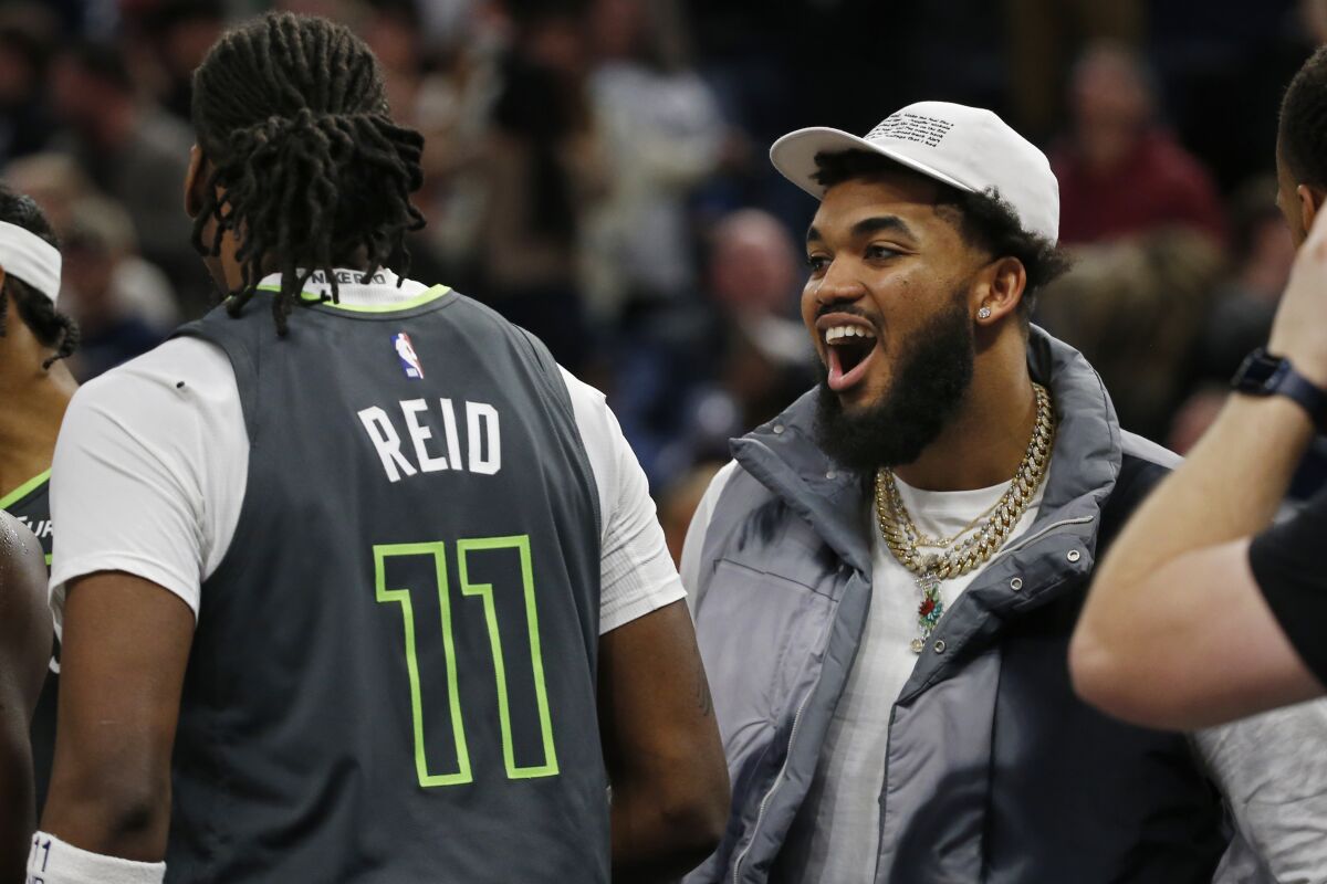 Injured Minnesota Timberwolves center Karl-Anthony Towns, right, celebrates after a three-point basket by teammate Naz Reid (11) to send an NBA basketball game against the Brooklyn Nets into overtime Friday, March 10, 2023, in Minneapolis. (AP Photo/Bruce Kluckhohn)