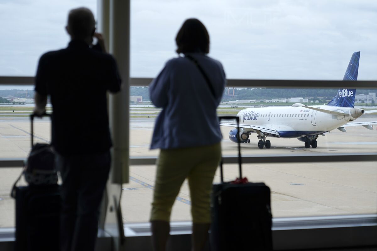 FILE - In this Tuesday, May 25, 2021 file photo, travelers watch a JetBlue Airways aircraft taxi away from a gate at Ronald Reagan Washington National Airport in Arlington, Va. According to three people familiar with the situation who spoke on Friday, Oct. 1, 2021, Alaska Airlines and JetBlue are joining United Airlines in requiring employees to be vaccinated against COVID-19, just as the Biden administration steps up pressure on major U.S. carriers to require the shots. (AP Photo/Patrick Semansky, File)