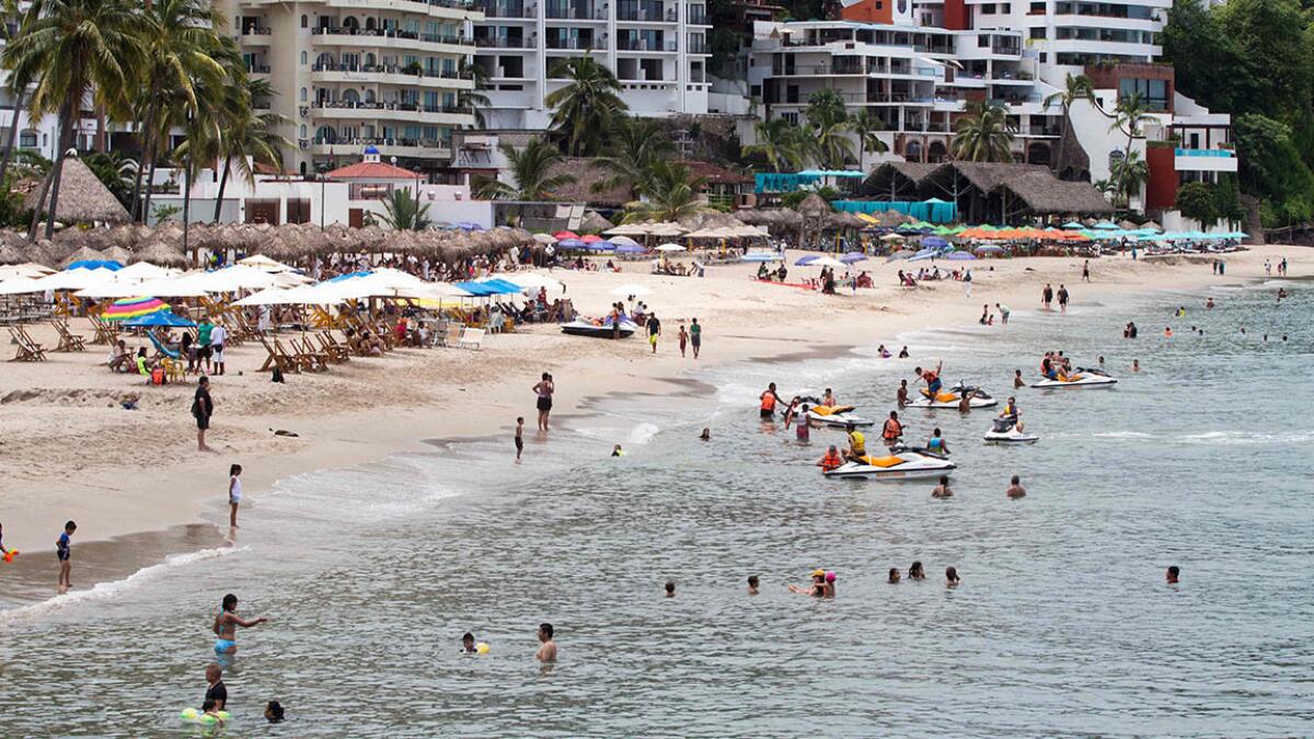 Sunbathers enjoy the beach at Puerto Vallarta, Mexico. A Southwest fare from Orange County to the Pacific Coast resort is available for $329.