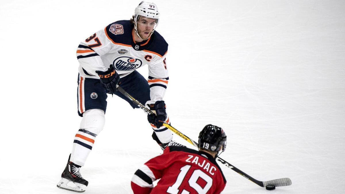 Edmonton's Connor McDavid tries to keep the puck away from New Jersey's Travis Zajac on Oct. 6.