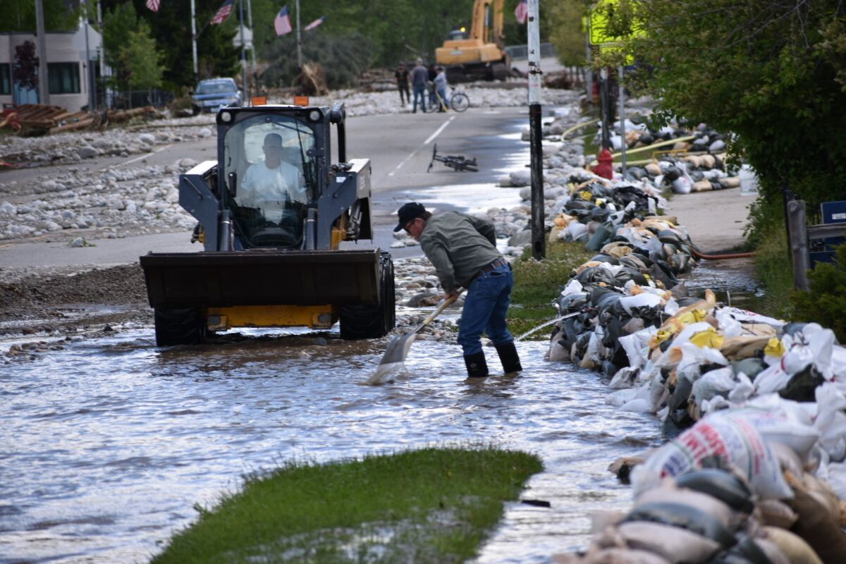 Residents of Red Lodge, Montana, are seen clearing mud, water and debris from the small city's main street on Tuesday, June 14, 2022, after flood waters courses through a residential area with hundreds of homes. (AP Photo/Matthew Brown)