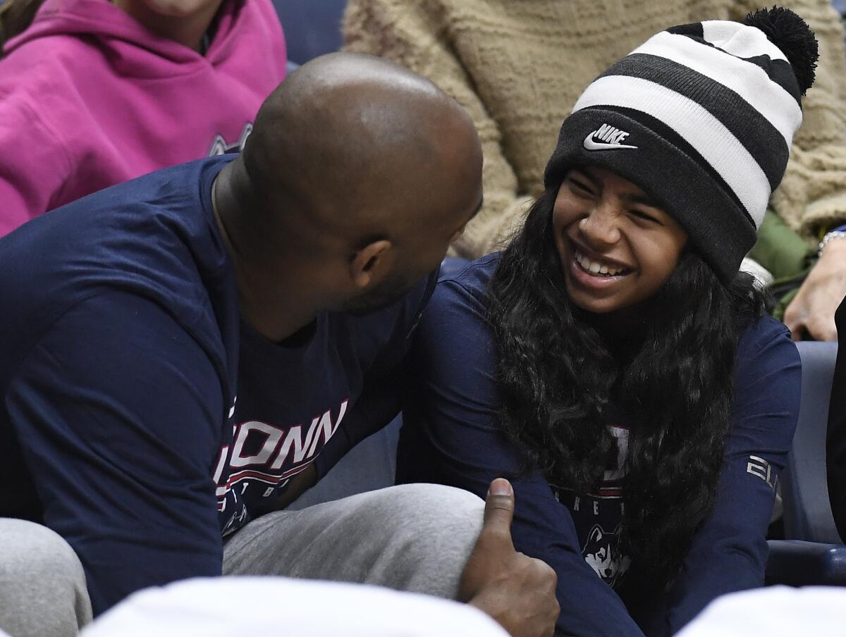 Kobe Bryant and his daughter Gianna watch the first half of an NCAA college basketball game between Connecticut and Houston.