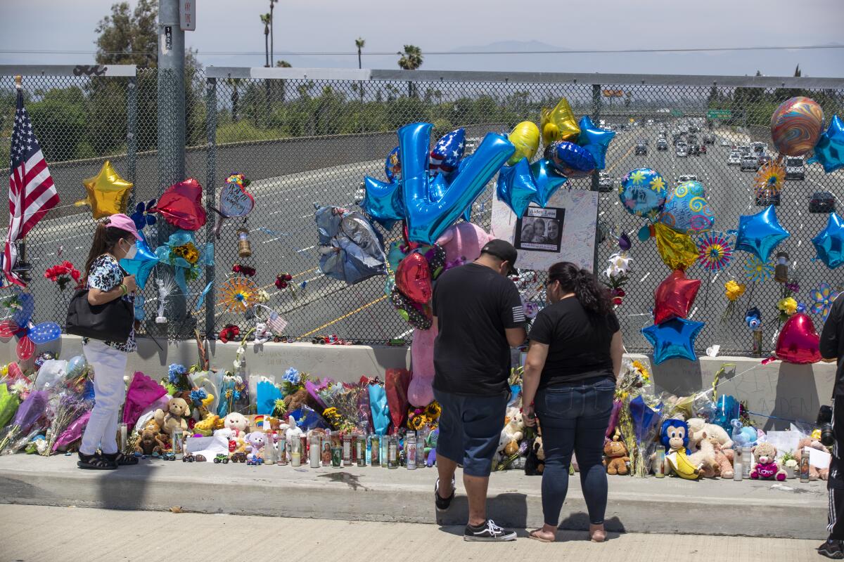 People stand in front of a memorial for 6-year-old Aiden Leos, who was fatally shot Friday on the 55 Freeway in Orange.