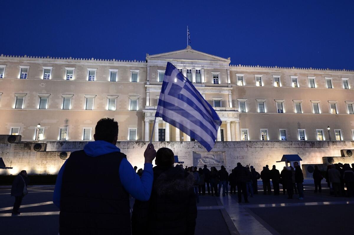 A man holds a Greek flag in front of the Parliament building in Athens at a rally in support of the new government on Feb. 20.