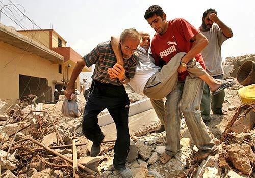 Residents carry the elderly and disabled through the rubble of Aaitaroun, Lebanon, as they attempt to leave. On the second day of a temporary cease fire, hundreds of people continued to flee their homes and villages, now mostly destroyed from the Israeli bombing.