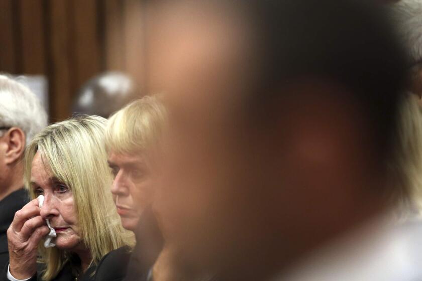 June Steenkamp wipes her face with a tissue at the start the trial of Oscar Pistorius, right, at the high court in Pretoria, South Africa, on Monday.