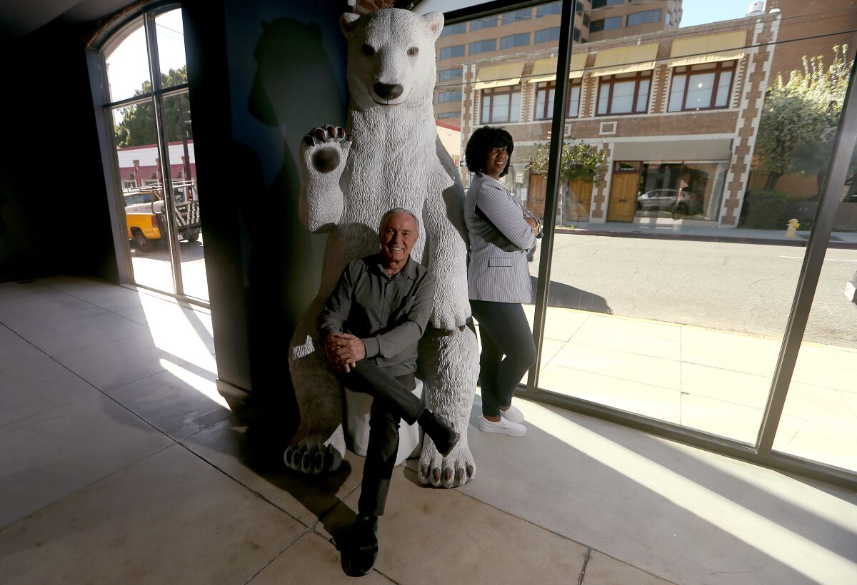 Man sits down on polar bear statue with woman leaning against it
