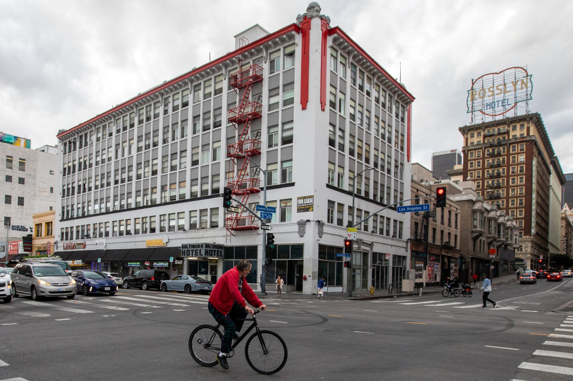 An exterior of the Baltimore Hotel with street in front of it and a man on a bicycle.