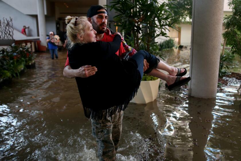 CaroLine Kirkpatrick of Salt Lake City is carried through the lobby of the Omni Hotel by rescue worker Adam Caballero as mandatory evacuation orders were in effect after the Addicks Reservoir overflowed Tuesday.