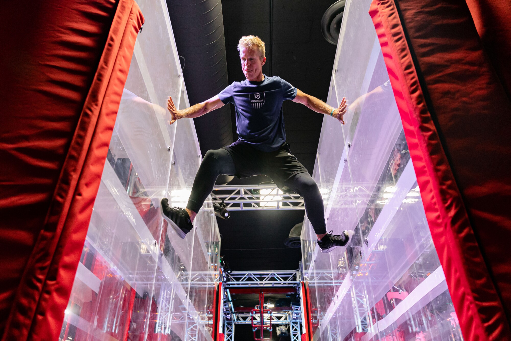A man balances between two vertical walls at an obstacle course.