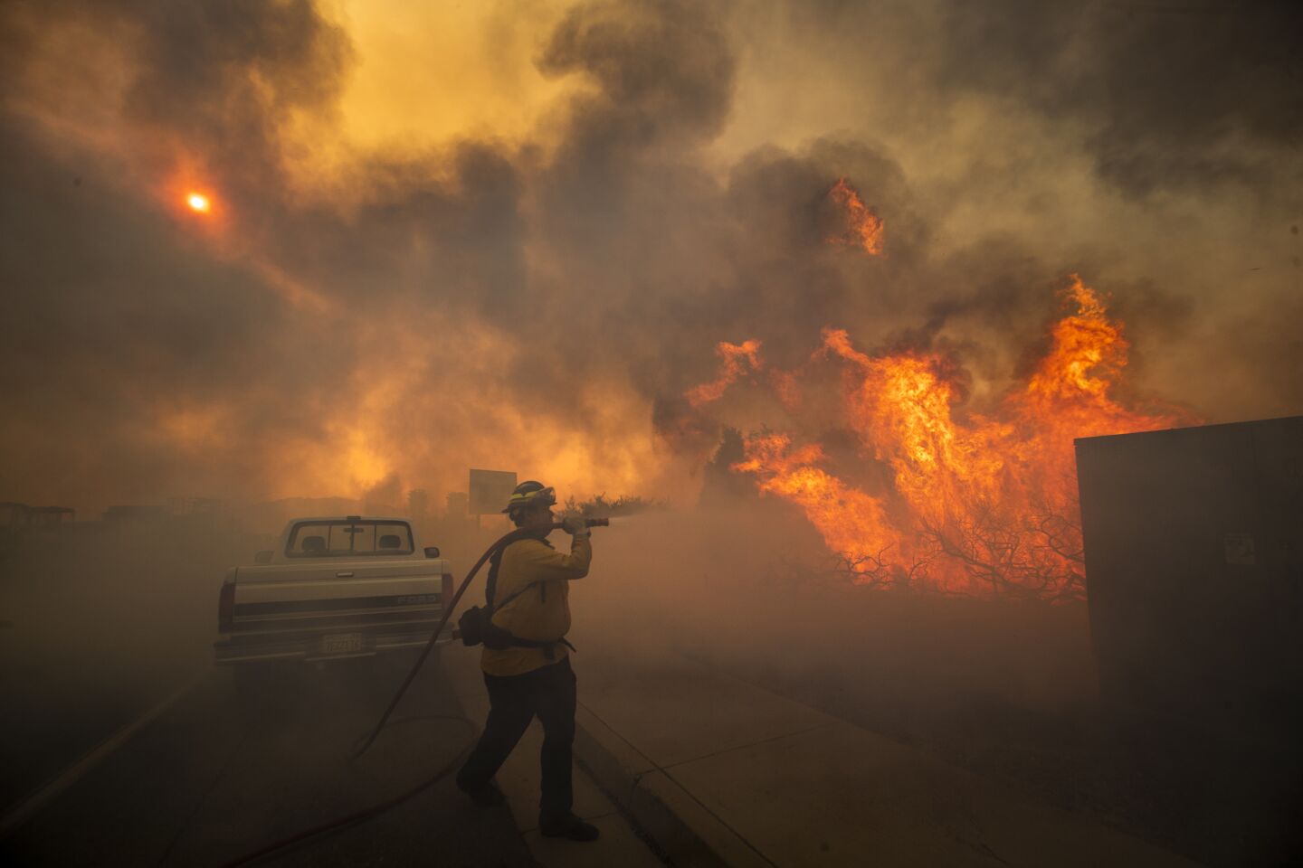 A firefighter amid smoke sprays water on flames