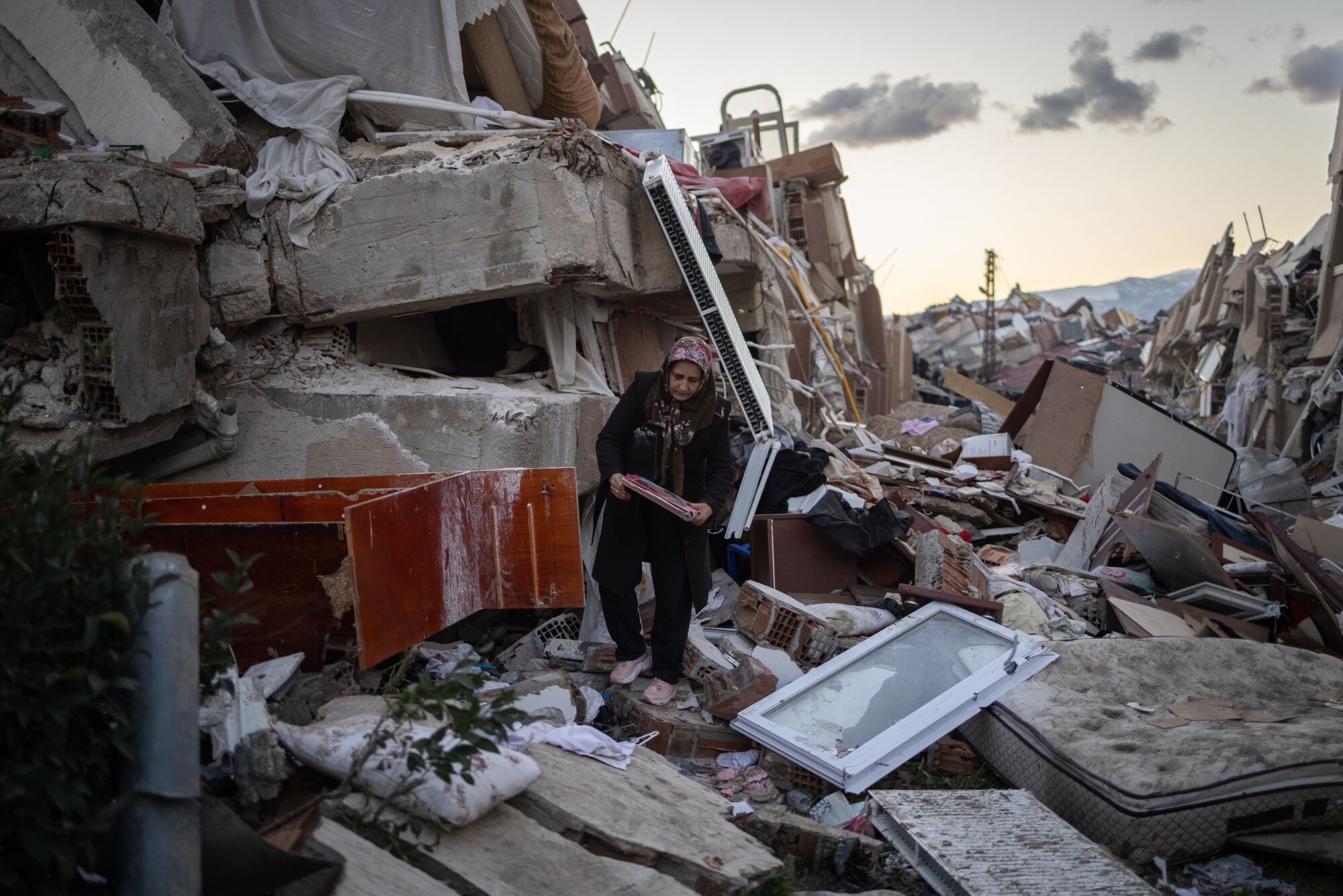 Crews search for Turkey earthquake victims as death tolls climbs A woman collects items from a destroyed home in Antakya, Turkey.