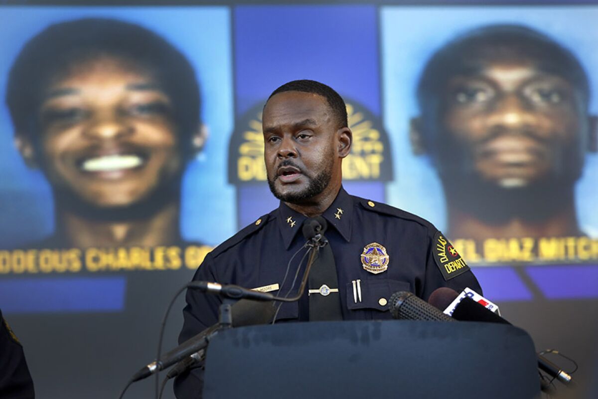 Avery Moore, assistant chief of police in Dallas, addresses the media on Tuesday about the death of Joshua Brown. Two of the three suspects, Thaddeous Green, left, and Michael Mitchell, are pictured in the background.