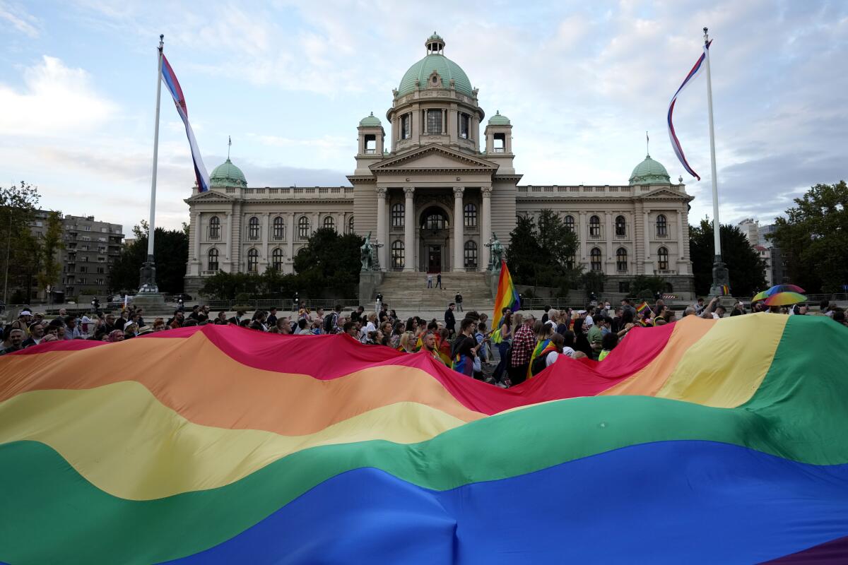 FILE - Participants carry large rainbow flag in front of the parliament building as they take part in the annual LGBT pride march in Belgrade, Serbia, Saturday, Sept. 18, 2021. Serbia's police on Tuesday banned an international Pride march that is to be held later this week, citing a risk of clashes between gay rights activists and far-right opponents of a pan-European LGBTQ events planned for this week in Belgrade. (AP Photo/Darko Vojinovic, File)