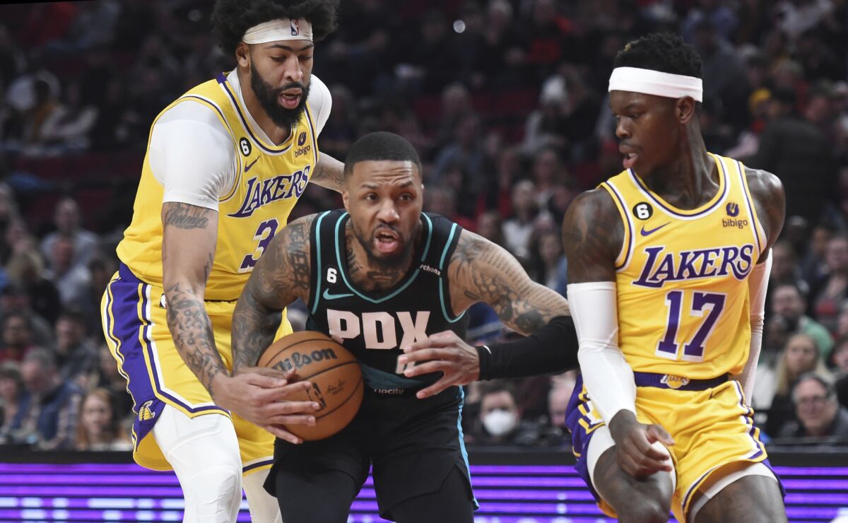 Trail Blazers guard Damian Lillard drives to the basket in front of Lakers forward Anthony Davis and guard Dennis Schroder