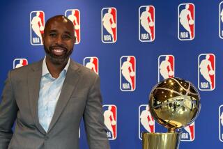 Albert Sanders, NBA executive vice president, stands next to the Larry O'Brien Trophy.