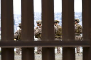 People in fatigues are seen through the slats of a wall