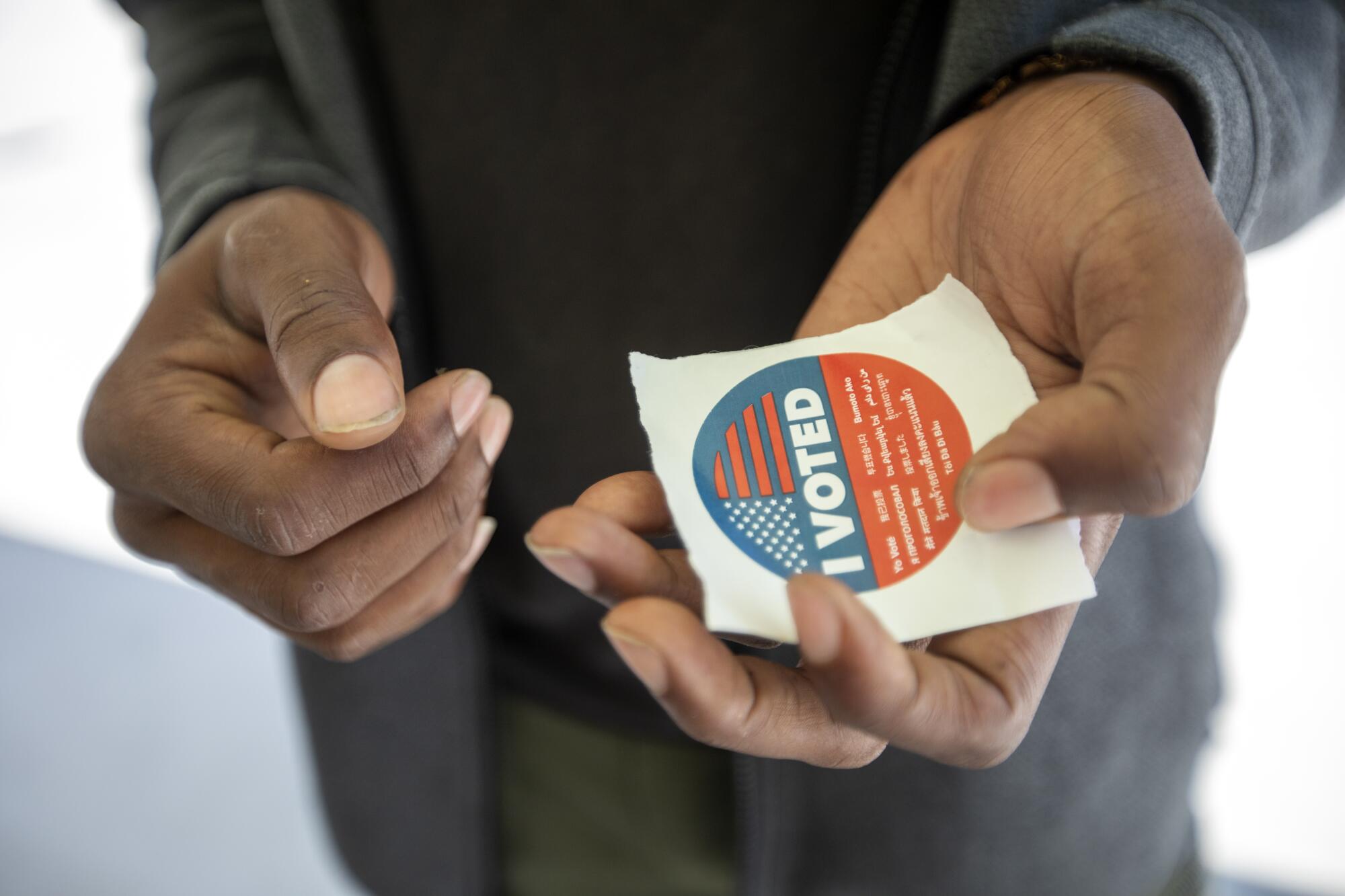 Hands hold an "I Voted" sticker